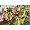 breakfast kiwi and cucumber smoothie bowl topped with avocado and flaxseeds in woman's hand on a cute wooden board with a green napkin, flat lay. Super Food
