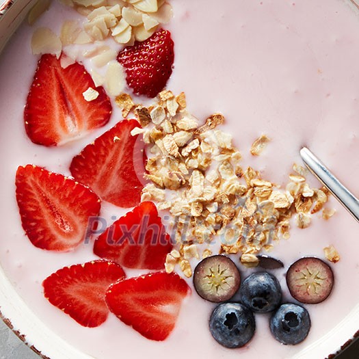Close-up of homemade yogurt with ripe strawberries, blueberries, granola and almonds shot from above, healthy vitamin breakfast Close-up of homemade yogurt with ripe strawberries, blueberries, granola and almonds shot from above, healthy vitamin breakfast