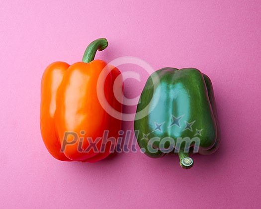 Orange and green peppers on a pink paper background. Organic vegetables. The concept of a healthy diet. Top view Orange and green peppers on a pink paper background. Organic vegetables. The concept of a healthy diet. Top view
