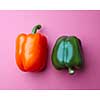Orange and green peppers on a pink paper background. Organic vegetables. The concept of a healthy diet. Top view