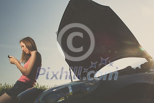 Pretty, young woman by the roadside after her car has broken down Pretty, young woman by the roadside after her car has broken down