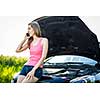 Pretty, young woman by the roadside after her car has broken down