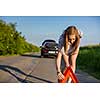 Pretty, young woman setting the safety triangle on the roadside after her car has broken down