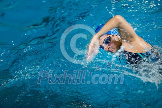 Female swimmer in an indoor swimming pool - doing crawl (shallow DOF) Female swimmer in an indoor swimming pool - doing crawl (shallow DOF)