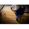 DIY, repair, building and home concept - close up of male hands lying parquet floor board/laminate flooring (shallow DOF; color toned image)