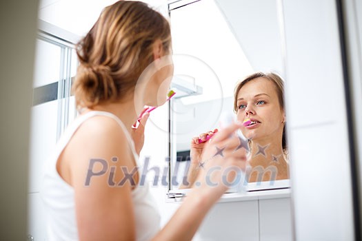 Pretty female brushing her teeth in front of mirror in the morning Pretty female brushing her teeth in front of mirror in the morning