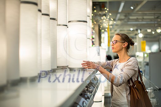 Pretty, young woman choosing the right light for her appartment in a modern home furnishings store (color toned image; shallow DOF) Pretty, young woman choosing the right light for her appartment in a modern home furnishings store (color toned image; shallow DOF)