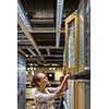 Pretty, young woman choosing the right furniture for her apartment in a modern home furnishings store (color toned image; shallow DOF)