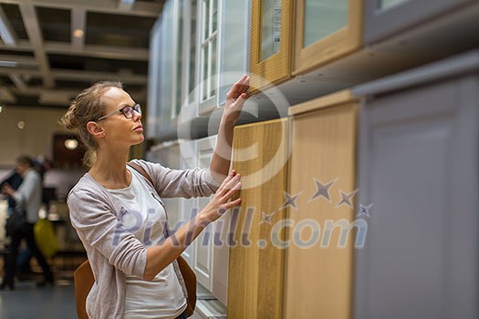 Pretty, young woman choosing the right furniture for her apartment in a modern home furnishings store (color toned image; shallow DOF) Pretty, young woman choosing the right furniture for her apartment in a modern home furnishings store (color toned image; shallow DOF)