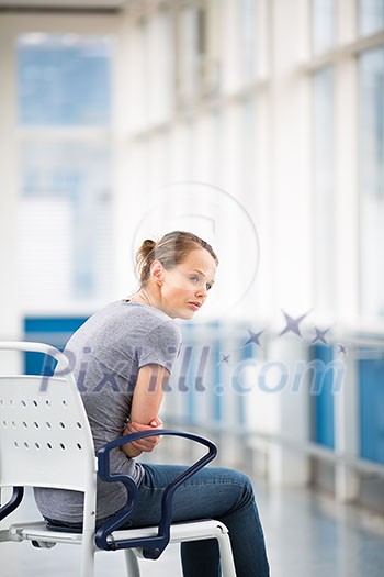 Female patient, sitting in a wheelchair for patients feeling not well enough to stand, waiting to be taken care of in a modern hospital (shallow DOF; color toned image) Female patient, sitting in a wheelchair for patients feeling not well enough to stand, waiting to be taken care of in a modern hospital (shallow DOF; color toned image)