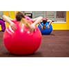 Group people in a pilates class at the gym - young woman with gymball at fitness training (shallow DOF, color toned image)