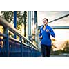 Young woman running outdoors, in a city, over a bridge