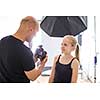 Teenage fashion model being shot by a photographer in a studio