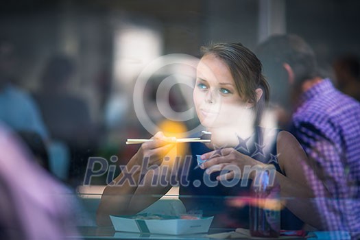 Pretty, young woman eating sushi in a restaurant, having her lunch break, enjoying the food, pausing for a while from her busy corporate/office life (color toned image) Pretty, young woman eating sushi in a restaurant, having her lunch break, enjoying the food, pausing for a while from her busy corporate/office life (color toned image)
