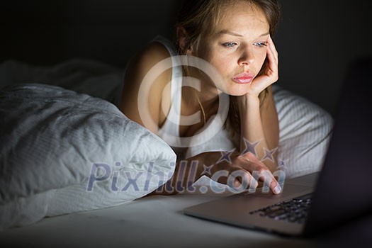 Pretty, young woman using her laptop computer in bed (color toned image; shallow DOF) Pretty, young woman using her laptop computer in bed (color toned image; shallow DOF)