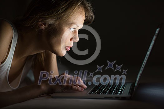 Pretty, young woman using her laptop computer in bed (color toned image; shallow DOF) Pretty, young woman using her laptop computer in bed (color toned image; shallow DOF)