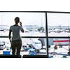 Pretty, young woman waiting at a gate area of a modern airport for  the boarding call - making some calls(color toned image; shallow DOF)