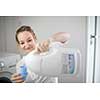 Housework: young woman doing laundry - putting colorful garments into the washing machine (shallow DOF; color toned image)