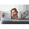 Pretty, young woman in her bed using her tablet computer, staying up to date with news and socail networks she likes(color toned image; shallow DOF)