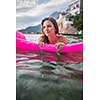 Pretty, young woman enjoying a day at the beach, relaxing on inflatable mattress