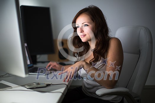 Young woman sitting and working on a computer in a home office Young woman sitting and working on a computer in a home office