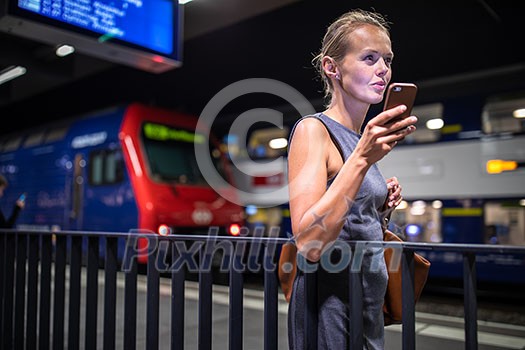 Pretty, young female commuter waiting for her daily train in a modern trainstation, using her cellphone while waiting (color toned image) Pretty, young female commuter waiting for her daily train in a modern trainstation, using her cellphone while waiting (color toned image)
