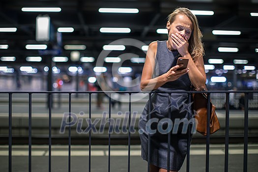 Pretty, young female commuter, looking exhausted, waiting for her daily train in a modern trainstation, using her cellphone while waiting (color toned image) Pretty, young female commuter, looking exhausted, waiting for her daily train in a modern trainstation, using her cellphone while waiting (color toned image)