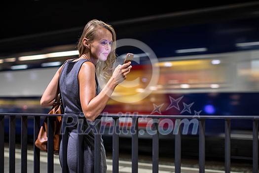 Pretty, young female commuter waiting for her daily train in a modern trainstation, using her cellphone while waiting (color toned image) Pretty, young female commuter waiting for her daily train in a modern trainstation, using her cellphone while waiting (color toned image)