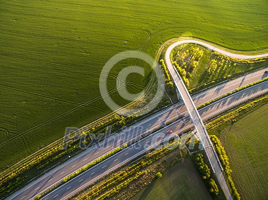 Aerial view of a highway amid fields with cars on it Aerial view of a highway amid fields with cars on it