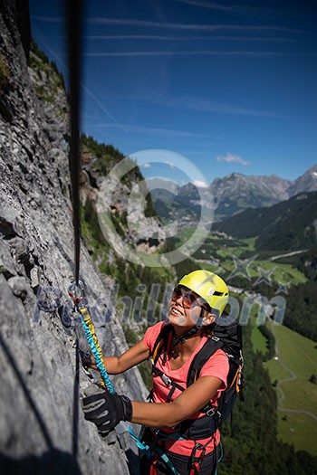 Pretty, female climber on a via ferrata - climbing on a rock in Swiss Alps Pretty, female climber on a via ferrata - climbing on a rock in Swiss Alps