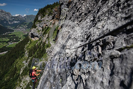 Pretty, female climber on a via ferrata - climbing on a rock in Swiss Alps Pretty, female climber on a via ferrata - climbing on a rock in Swiss Alps