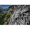 Pretty, female climber on a via ferrata - climbing on a rock in Swiss Alps