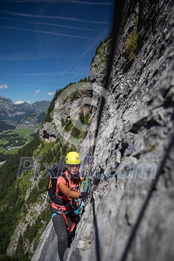 Pretty, female climber on a via ferrata - climbing on a rock in Swiss Alps Pretty, female climber on a via ferrata - climbing on a rock in Swiss Alps