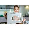 Pretty, young woman sewing clothes with sewing machine (color toned image; shallow DOF)