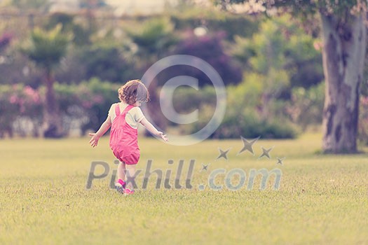 playful cute little girl cheerfully spending time while running in the spacious backyard on the grass playful cute little girl cheerfully spending time while running in the spacious backyard on the grass