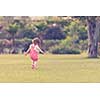 playful cute little girl cheerfully spending time while running in the spacious backyard on the grass