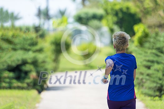 young sporty female runner training for marathon running at beautiful tropical park in the sunny morning young sporty female runner training for marathon running at beautiful tropical park in the sunny morning