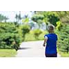 young sporty female runner training for marathon running at beautiful tropical park in the sunny morning
