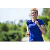 young sporty female runner training for marathon running at beautiful tropical park in the sunny morning