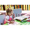 cute little girl cheerfully spending time using pencil crayons while drawing a colorful pictures in the outside playschool