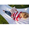 young woman reading a book while relaxing on hammock in a peaceful garden during holiday