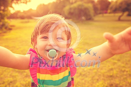 playful cute little girl cheerfully spending time while running in the spacious backyard on the grass playful cute little girl cheerfully spending time while running in the spacious backyard on the grass