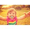 playful cute little girl cheerfully spending time while running in the spacious backyard on the grass