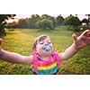 playful cute little girl cheerfully spending time while running in the spacious backyard on the grass