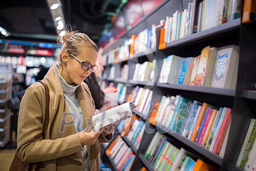 Pretty, young female choosing a good book to buy in a bookstore Pretty, young female choosing a good book to buy in a bookstore