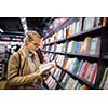 Pretty, young female choosing a good book to buy in a bookstore