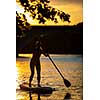 SUP Stand up paddle board concept - Pretty, young woman paddle boarding on a lovely lake in warm late afternoon light - shot from underwater