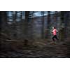 Young woman running outdoors in a forest, going fast (motion blurred image)