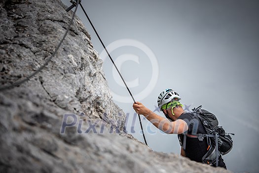 Pretty, female climber on a via ferrata - climbing on a rock in Swiss Alps Pretty, female climber on a via ferrata - climbing on a rock in Swiss Alps