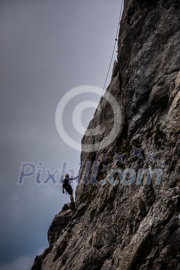 Pretty, female climber on a via ferrata - climbing on a rock in Swiss Alps Pretty, female climber on a via ferrata - climbing on a rock in Swiss Alps